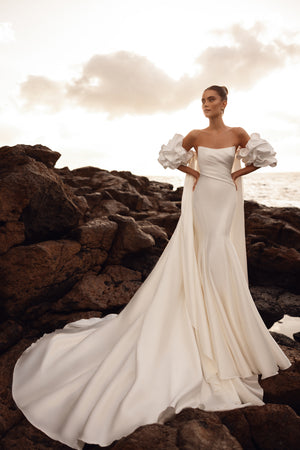 Elegancka suknia ślubna z długim trenem i efektownymi bufkami na ramionach, idealna na nowoczesny ślub glamour.