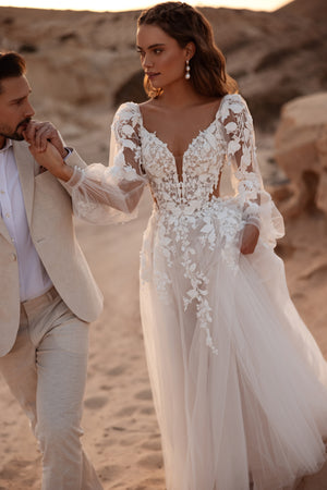 Suknia ślubna Alia od DAMA Couture posiada dopasowany gorset z trójwymiarową koronką i głęboki dekolt w kształcie V, który subtelnie modeluje talię.