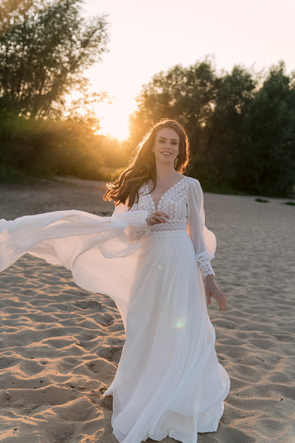 Suknia ślubna w stylu boho z długim rękawem, wiązaniem na plecach oraz zwiewną spódnicą z rozporkiem z pracowni sukien ślubnych Dama Couture (zdjęcie główne)