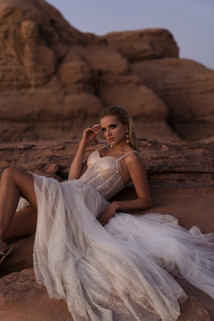 Panna młoda w sukni Inca oparta na skale, rozłożony tiul i skrzący się gorset