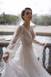 Błyszcząca suknia ślubna w stylu księżniczki z długimi bufiastymi rękawami, głębokim dekoltem oraz zwiewną spódnicą z pracowni sukien ślubnych Dama Couture (zdjęcie główne)