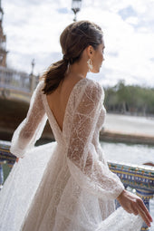 Błyszcząca suknia ślubna w stylu księżniczki z długimi bufiastymi rękawami, głębokim dekoltem oraz zwiewną spódnicą z pracowni sukien ślubnych Dama Couture (zdjęcie tył)