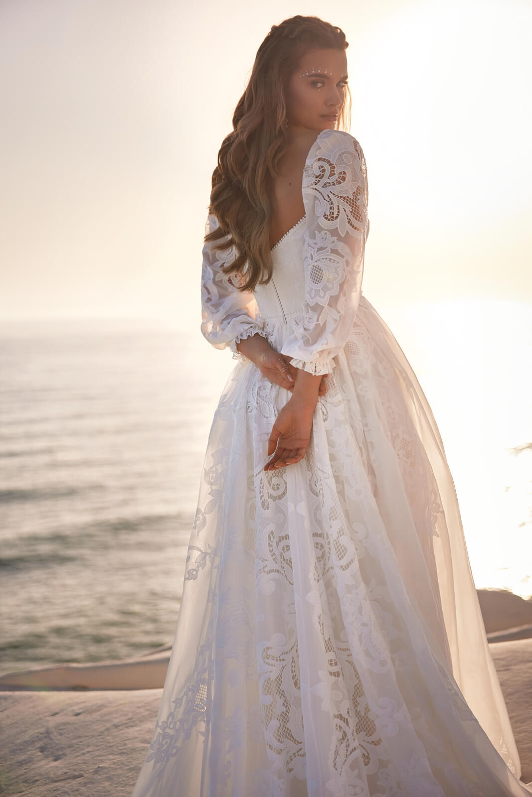 Suknia ślubna Rania nad morzem, panna młoda przez ramię, ażurowa koronka na bufiastych rękawach
