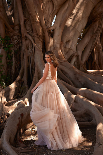 Kobieca suknia ślubna w odcieniach beżu na szerokich ramiączkach i wycięciach z boku gorsetu oraz rozkloszowaną, tiulową spódnicą z pracowni sukien ślubnych Dama Couture (zdjęcie tył)