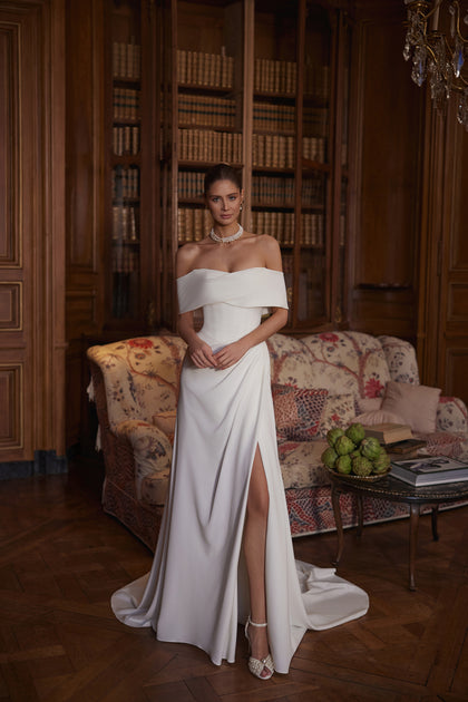 Calliope wedding dress – A-line bridal gown with a wide off-the-shoulder neckline and clean satin skirt with a slit.
