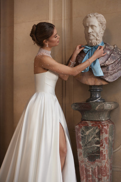 Lucienne wedding dress – a crystal-embellished illusion neckline and draped satin skirt with a high slit.