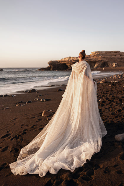 Amira bridal cape with long tulle train and delicate appliqués, perfect for beach weddings and modern brides.