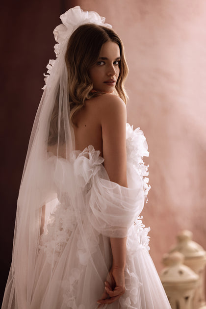 Close-up of the Bella wedding gown shows the detailed floral 3D bodice and sheer tulle fabric for a modern romantic touch.