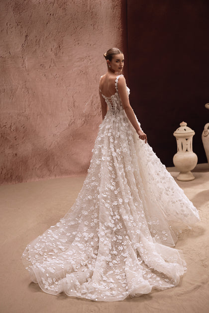 Suknia Cintra z pełną spódnicą ozdobioną trójwymiarowymi kwiatami i błyszczącymi detalami tworzy spektakularny, królewski efekt.