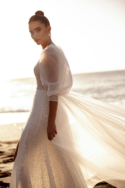 Suknia Davina z połyskującą strukturą i bufiastymi rękawami tworzy niezwykle kobiecy i pełen blasku wizerunek panny młodej.