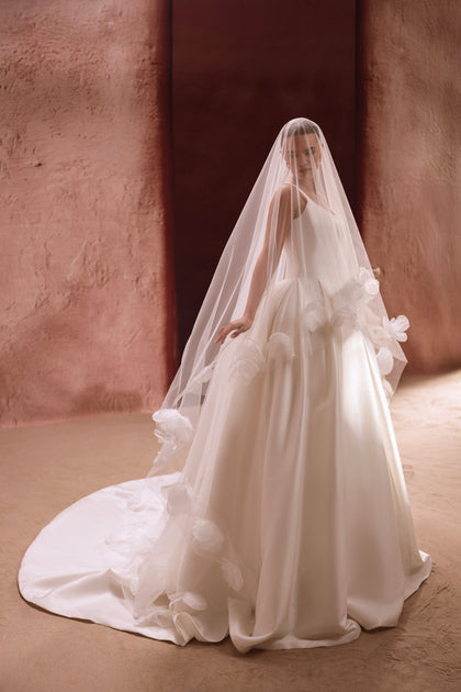 Długi welon ślubny z tiulu zdobionego kwiatowymi aplikacjami, tworzący romantyczną oprawę klasycznej sukni ślubnej.