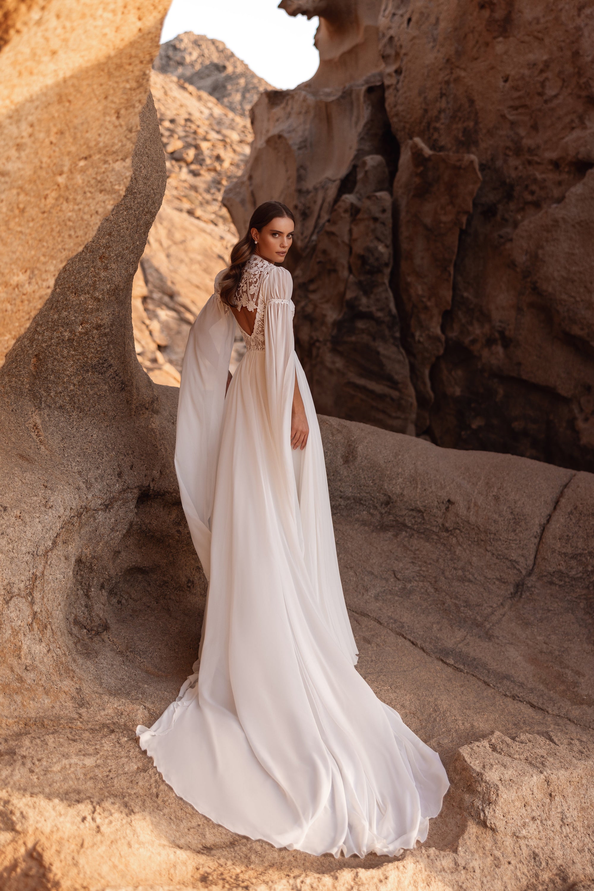 Suknia ślubna Etra od tyłu w całej sylwetce, rozcięte szyfonowe rękawy opadają jak peleryna