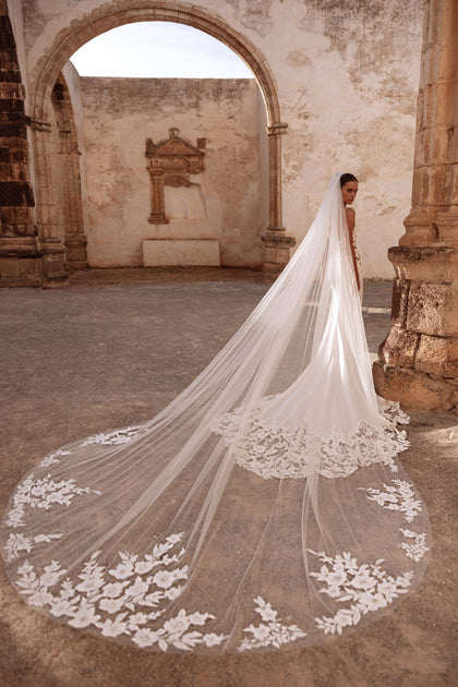 Munira cathedral wedding veil with floral lace appliqués, creating a dramatic bridal look in historic ruins.