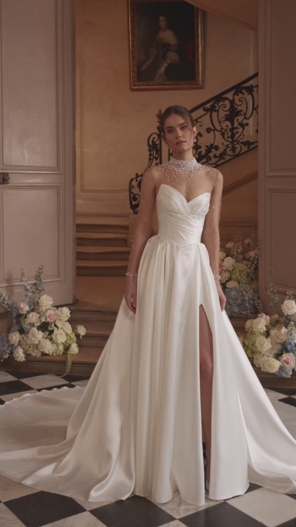 Video of the Lucienne wedding dress in motion – A-line silhouette with a crystal-embellished illusion neckline and draped satin skirt with a high slit.