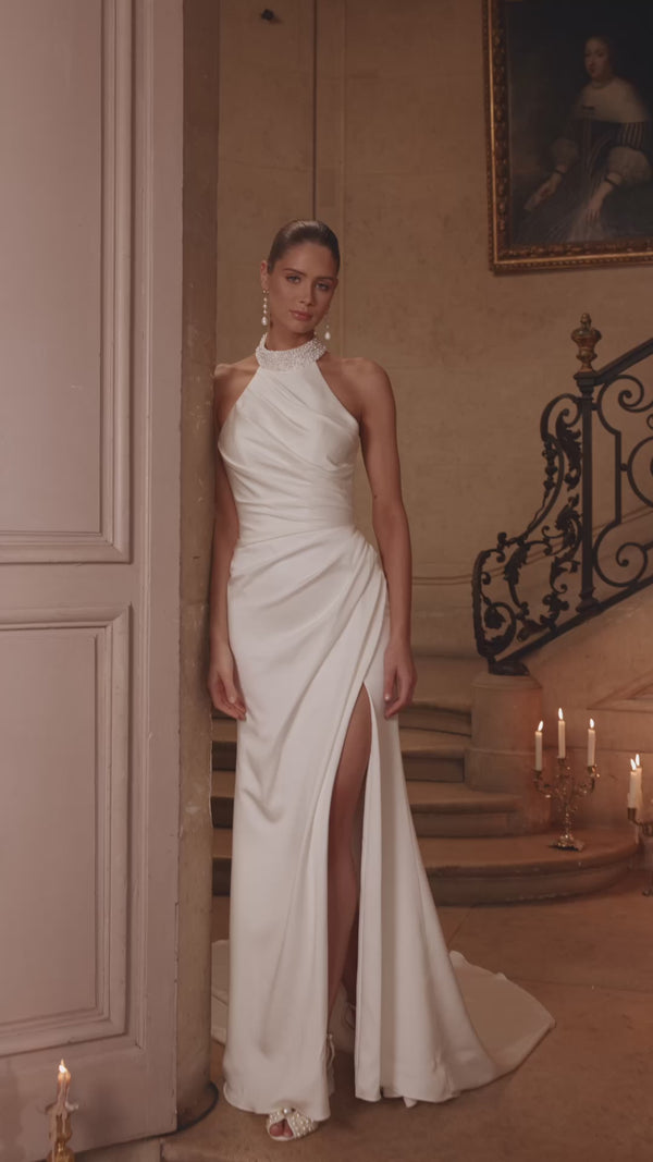 Video of the Camilla wedding dress in motion – mermaid silhouette with a pearl-embellished halter collar, wrap draping and thigh-high slit.