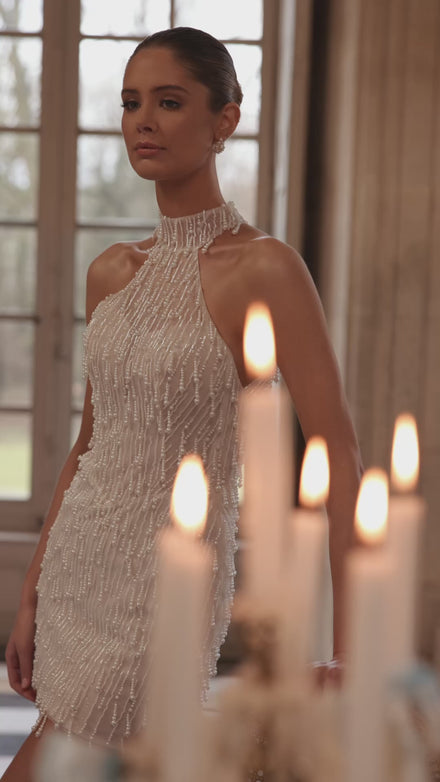 Video of the Rhea wedding dress in motion – short silhouette with a high halter neckline and cascading strands of pearls and crystals.