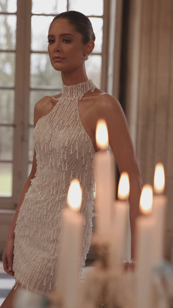 Video of the Rhea wedding dress in motion – short silhouette with a high halter neckline and cascading strands of pearls and crystals.