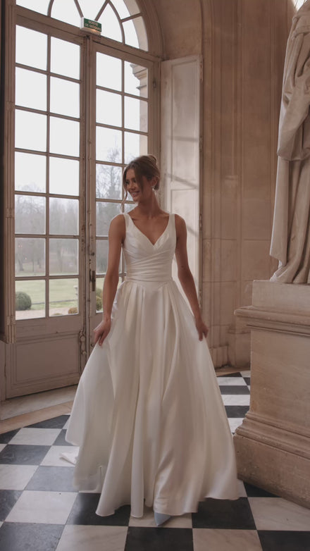 Video of the Elvira wedding dress in motion – A-line silhouette with an open V-neckline and clean draped skirt with a high slit.