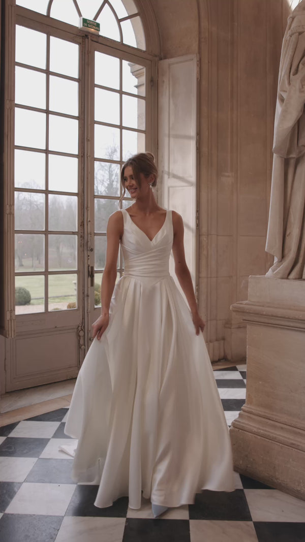 Video of the Elvira wedding dress in motion – A-line silhouette with an open V-neckline and clean draped skirt with a high slit.