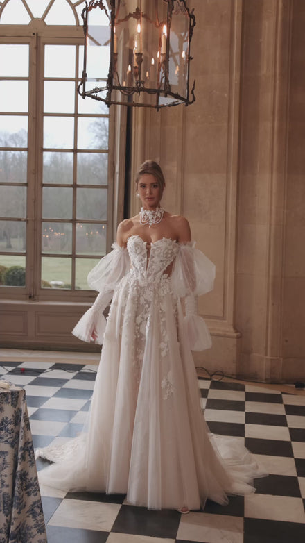 Video of the Estella wedding dress in motion – A-line silhouette with a dimensional floral corset and voluminous off-the-shoulder sleeves.