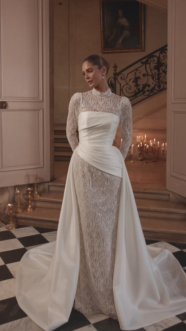 Video of the Juniona wedding dress in motion – mermaid silhouette with a high neckline, fitted long sleeves and geometric lace.