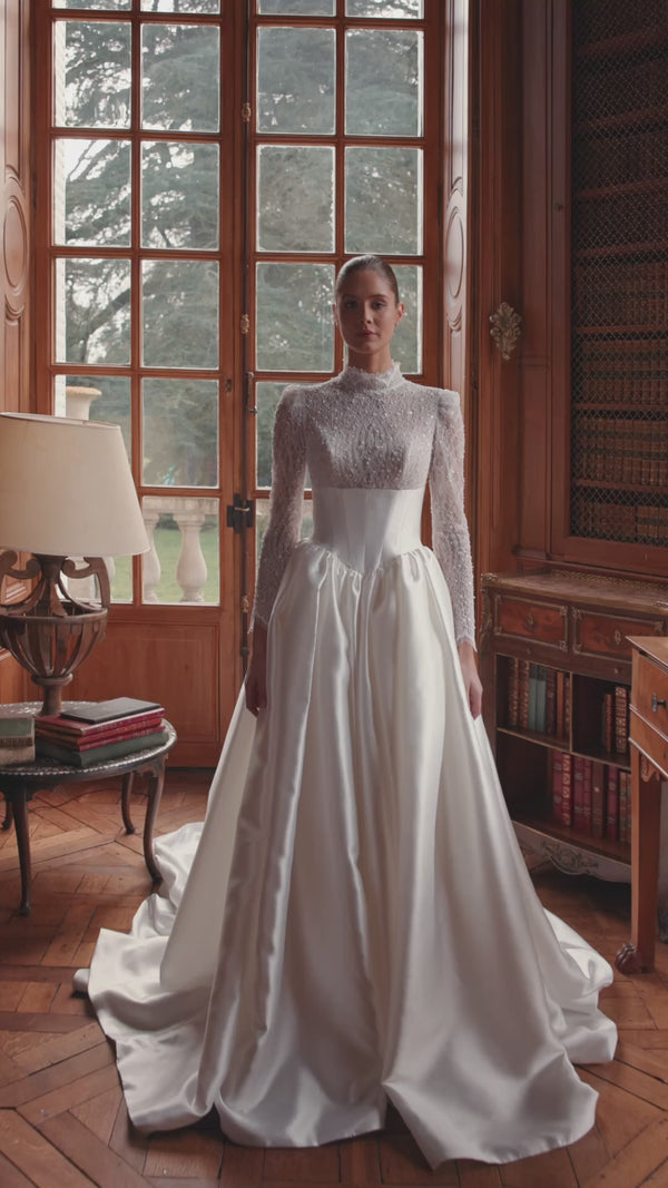 Video of the Maristella wedding dress in motion – A-line silhouette with a high-neck lace bodice with long sleeves and full satin skirt.