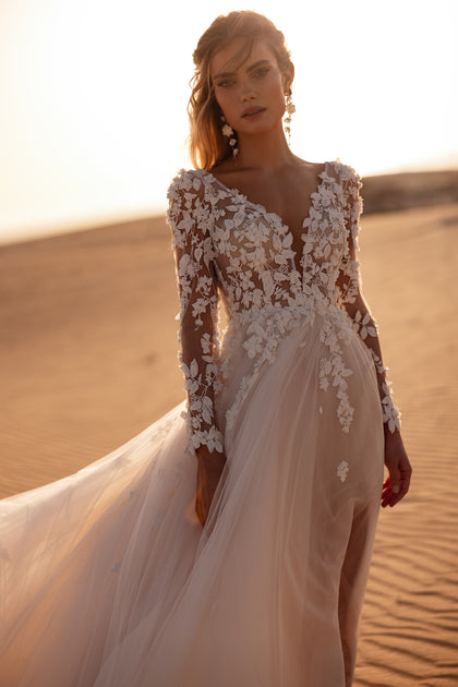 Suknia ślubna Farida z głębokim dekoltem w kształcie litery V i długimi koronkowymi rękawami zachwyca lekkością tiulu i kwiatowymi aplikacjami 3D.