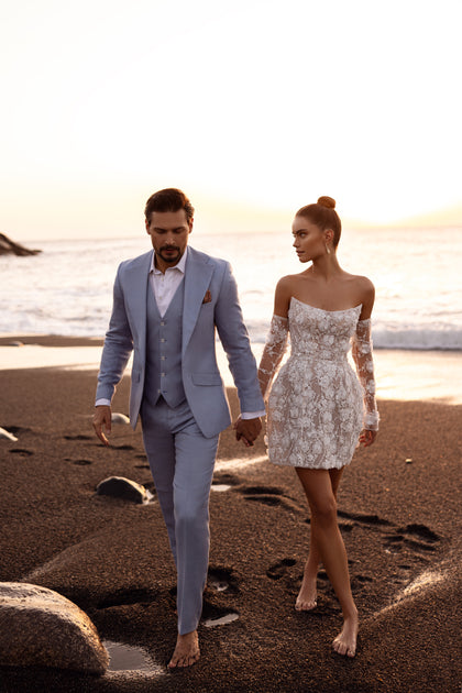 Krótka suknia ślubna Kayla z długimi, przezroczystymi rękawami i aplikacjami 3D to nowoczesna alternatywa dla klasycznej kreacji ślubnej.