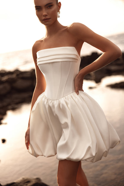 Suknia ślubna Martini mini z gorsetem typu bustier i efektowną bombką łączy nowoczesny minimalizm z kobiecym wdziękiem.