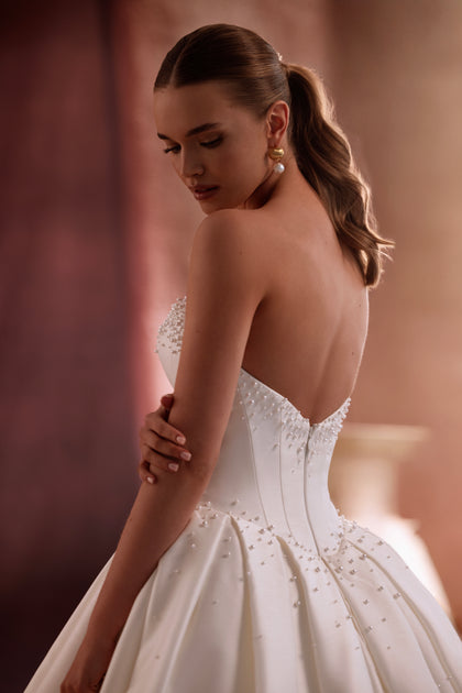 Suknia ślubna Noor z rozłożystą spódnicą i trenem zachwyca luksusowym połyskiem satyny i klasycznym kształtem w stylu haute couture.