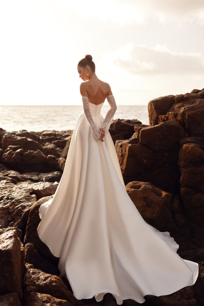 Zmysłowa suknia ślubna Sarabi z odkrytymi ramionami i rękawiczkami z pereł tworzy wyjątkowy efekt glamour.