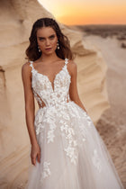 Romantyczna suknia ślubna Zafira z tiulowym dołem i kwiatowymi zdobieniami w towarzystwie pana młodego w beżowym garniturze.