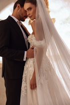 Subtelny welon ślubny Ariella z delikatnym tiulem i koronkowym zdobieniem pięknie komponuje się z romantyczną suknią ślubną.